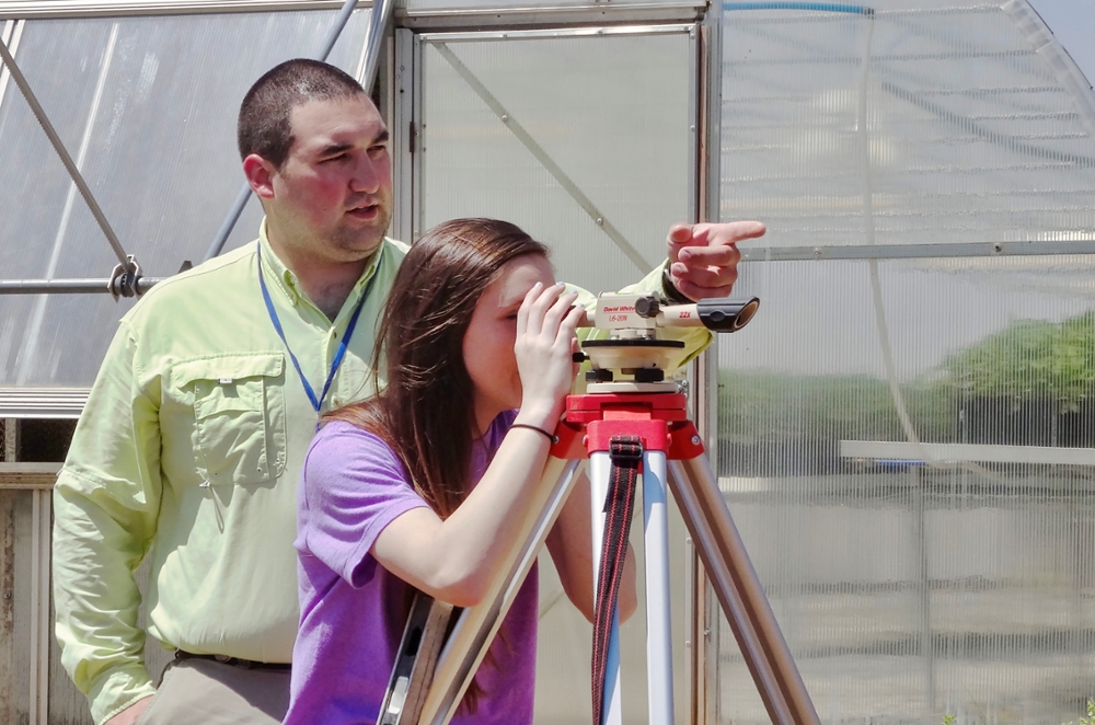 professor working in the field with an agricultural education graduate student 