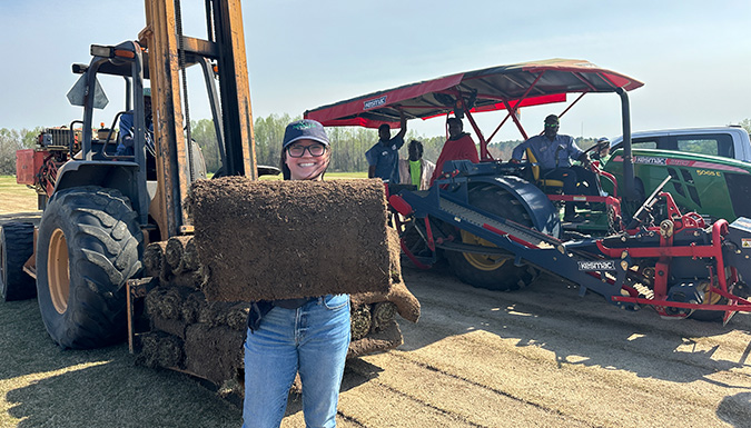 Student holding rolled up turf grass