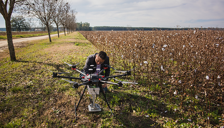joe mari maja working on a drone near a crop