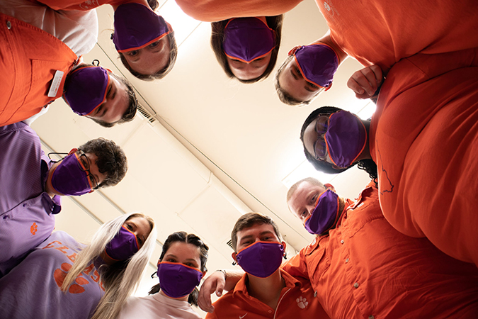 students standing in a circle looking down at the camera