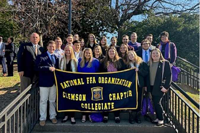 students posing for picture while holding banner