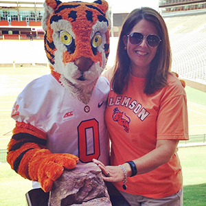 paula beecher posing with the clemson tiger mascot in front of the football stadium