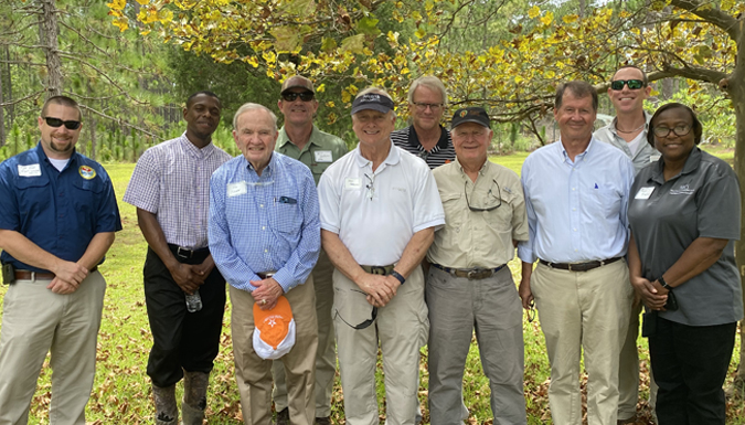 a group of the stakeholders posing for a photo outside under a tree