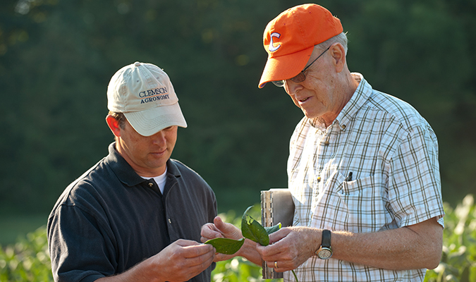 two farmers out in the field holding a plant