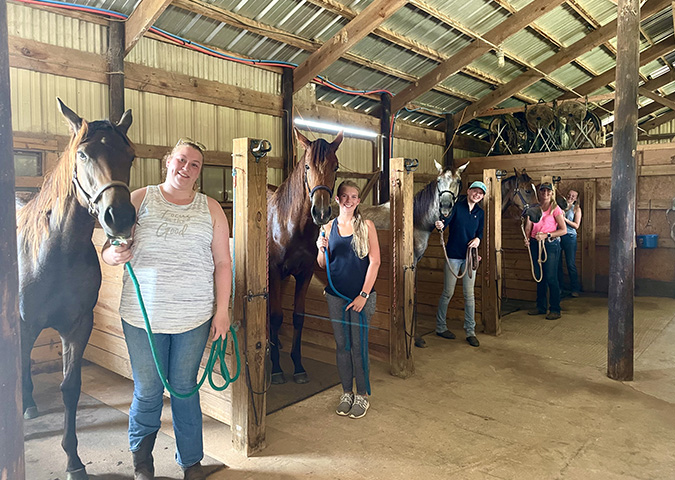 girls with horses in stalls