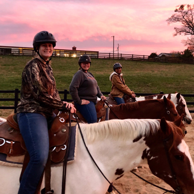 camp participants riding in a pasture at sunset