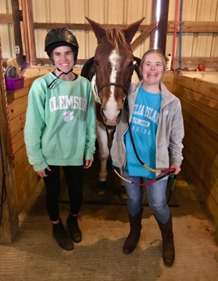 two girls smiling while standing with Pudge the horse