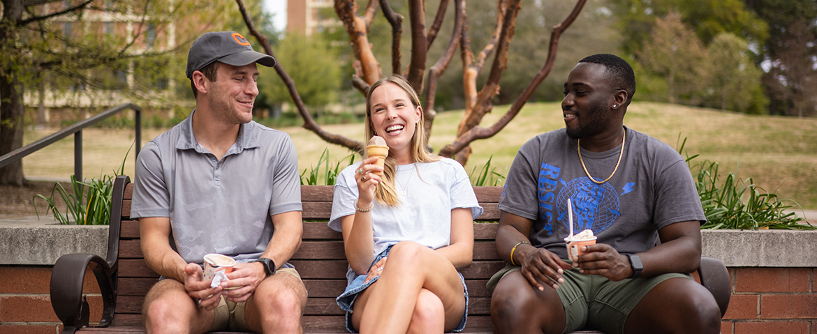 group smiling while eating ice cream on a bench outside 55 Exchange