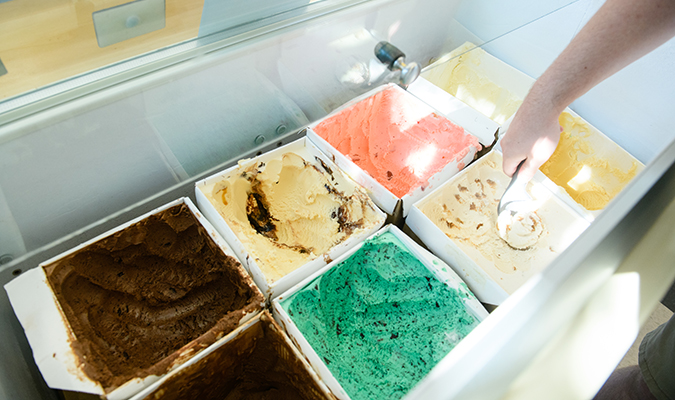 hand scooping ice cream from freezer display
