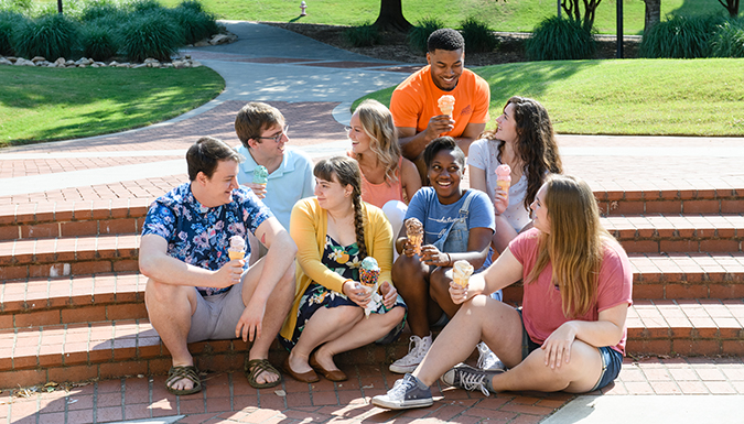 Group of students sitting on stairs outside of 55 exchange talking and eating ice cream