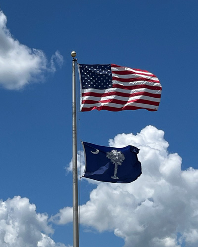 american flag and south carolina state flags raised on a flag pole