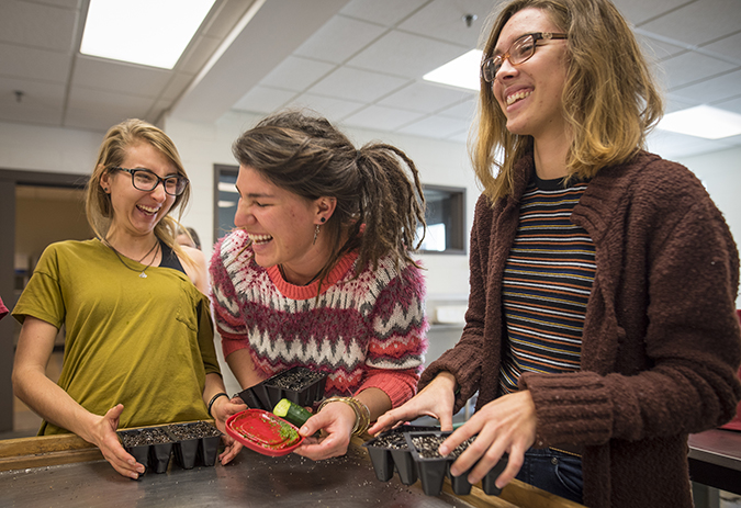 girls laughing while planting mango seeds