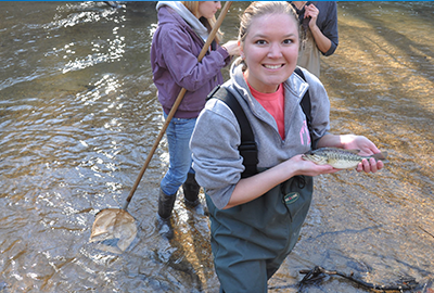 Student in water holding a fish