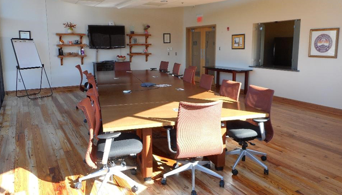 conference room with large table and chairs around, near a wall of windows overlooking treetops