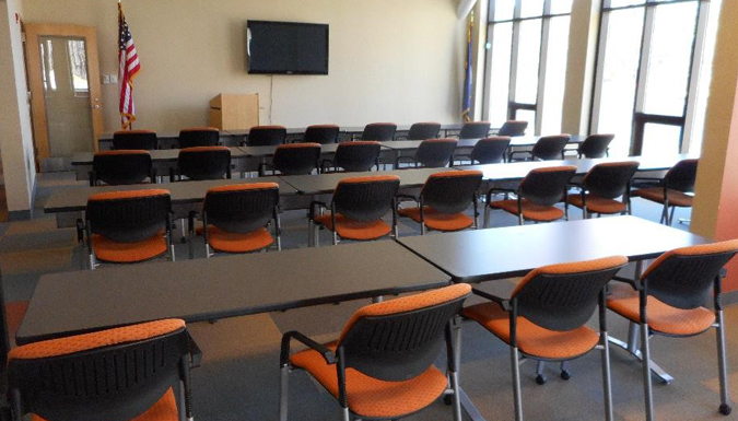conference room with large table and chairs around, near a wall of windows overlooking treetops