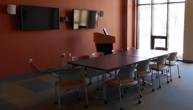 conference room with large table and chairs around, near a wall of windows overlooking treetops