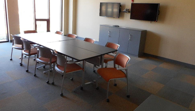 conference room with large table and chairs around, near a wall of windows overlooking treetops
