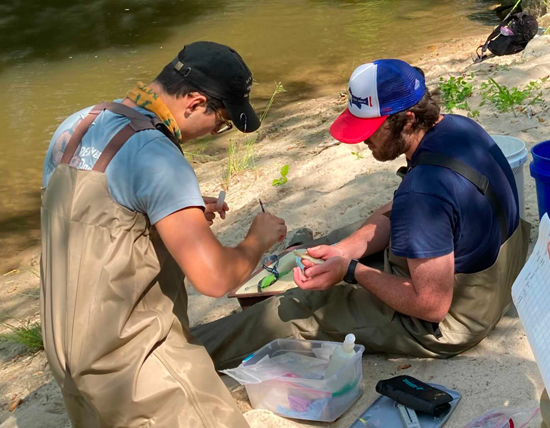 Drew Kanes working creekside with another student