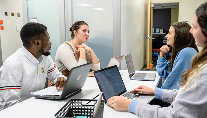 A group of four students talk at a table