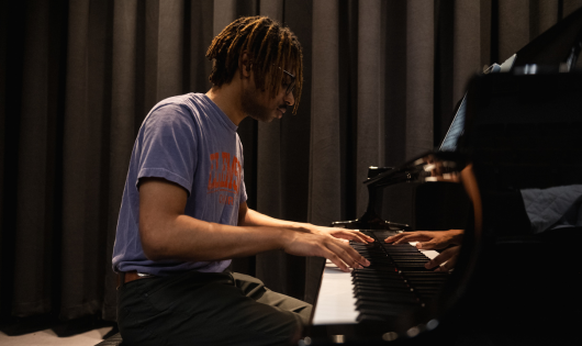 A clemson student rehearses on a piano in a recital hall