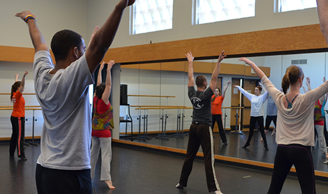 Students stretch in front of mirror in dance studio