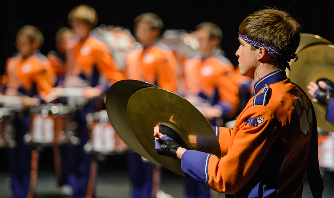 Members of Tiger Band line up in uniform with one cymbal player in focus