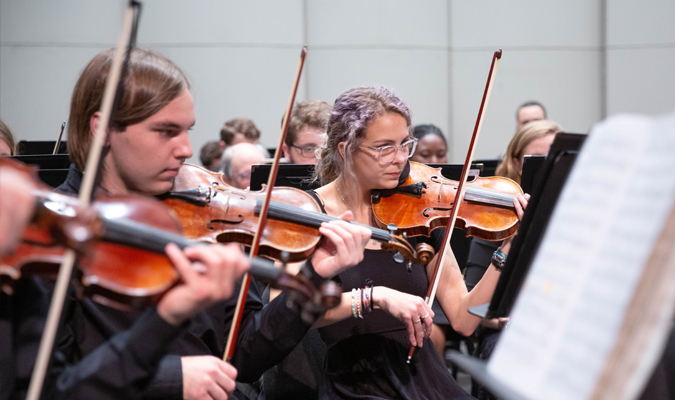 Violinists play as part of the orchestra