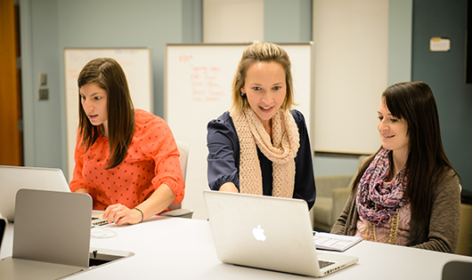 professor and students discussing content on a laptop screen