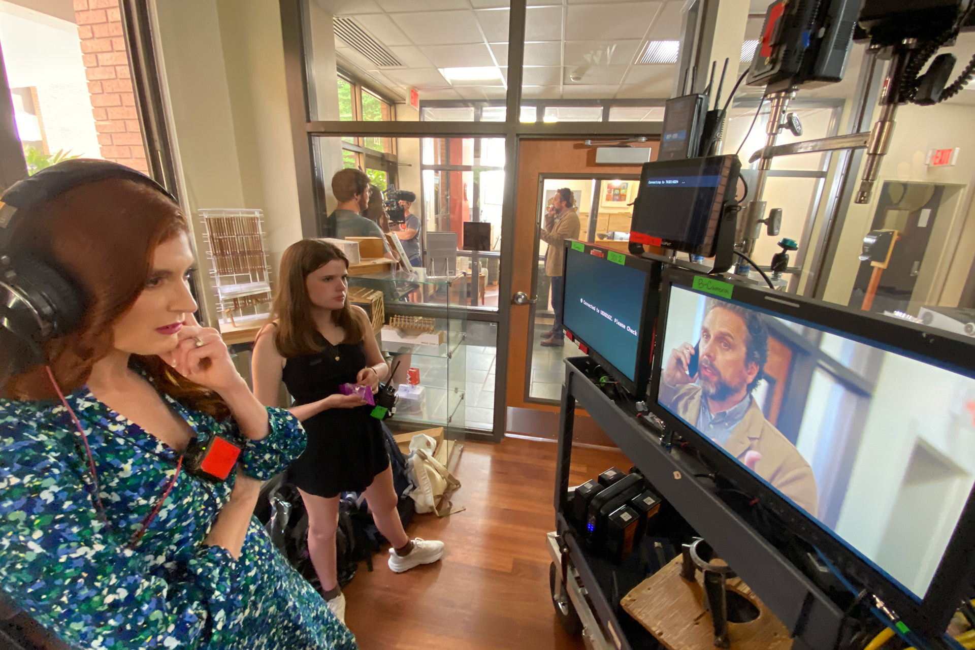 A person wearing headphones looks thoughtfully at a screen