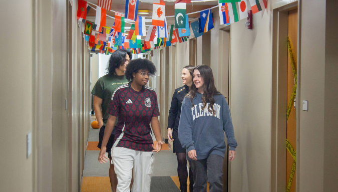 People walking in a hallway with flags from many countries.