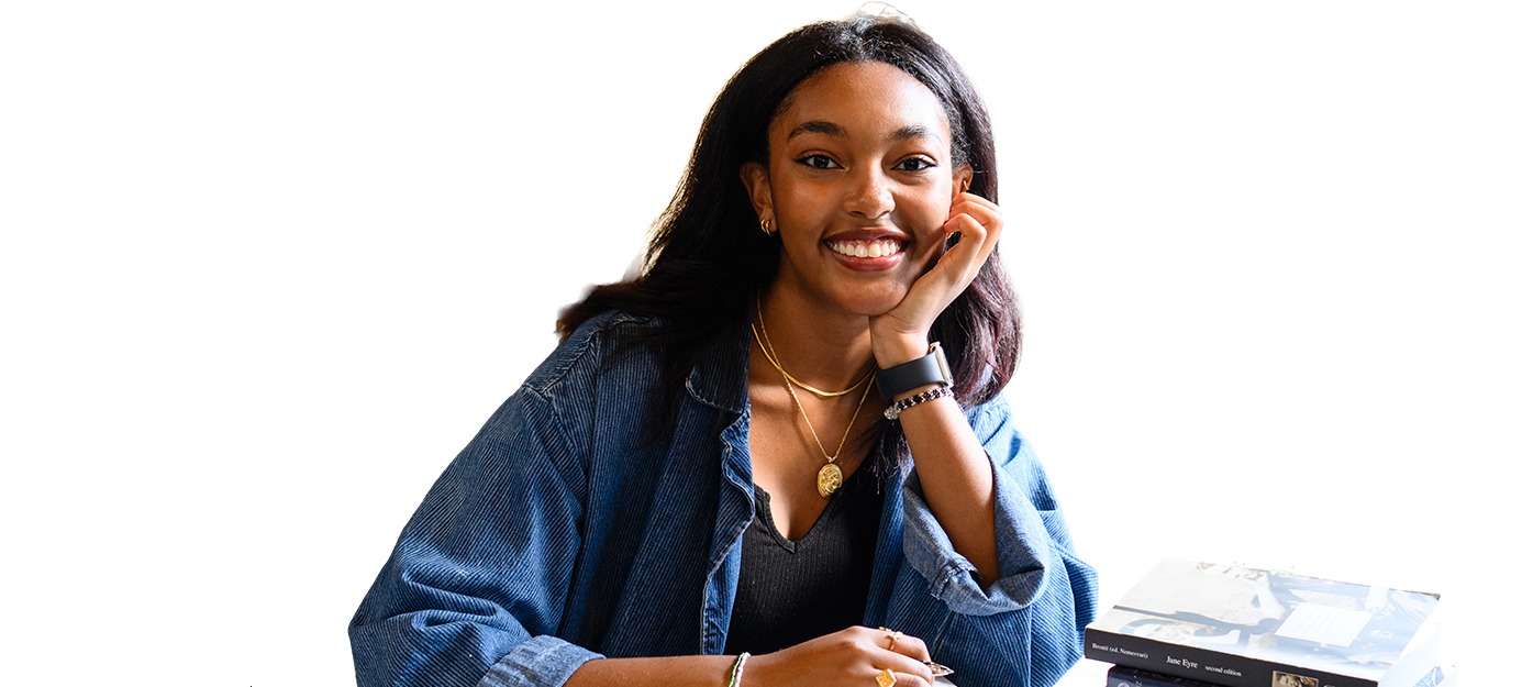 A person smiling with a pen and books.