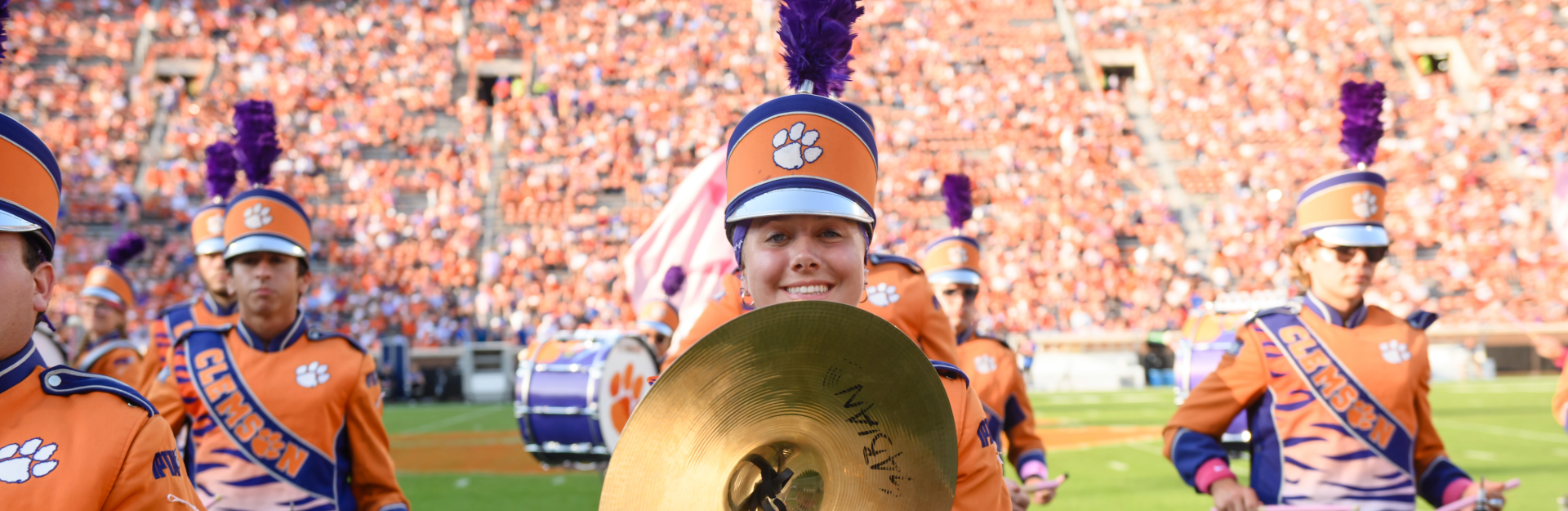 Members of a marching band smile on a field