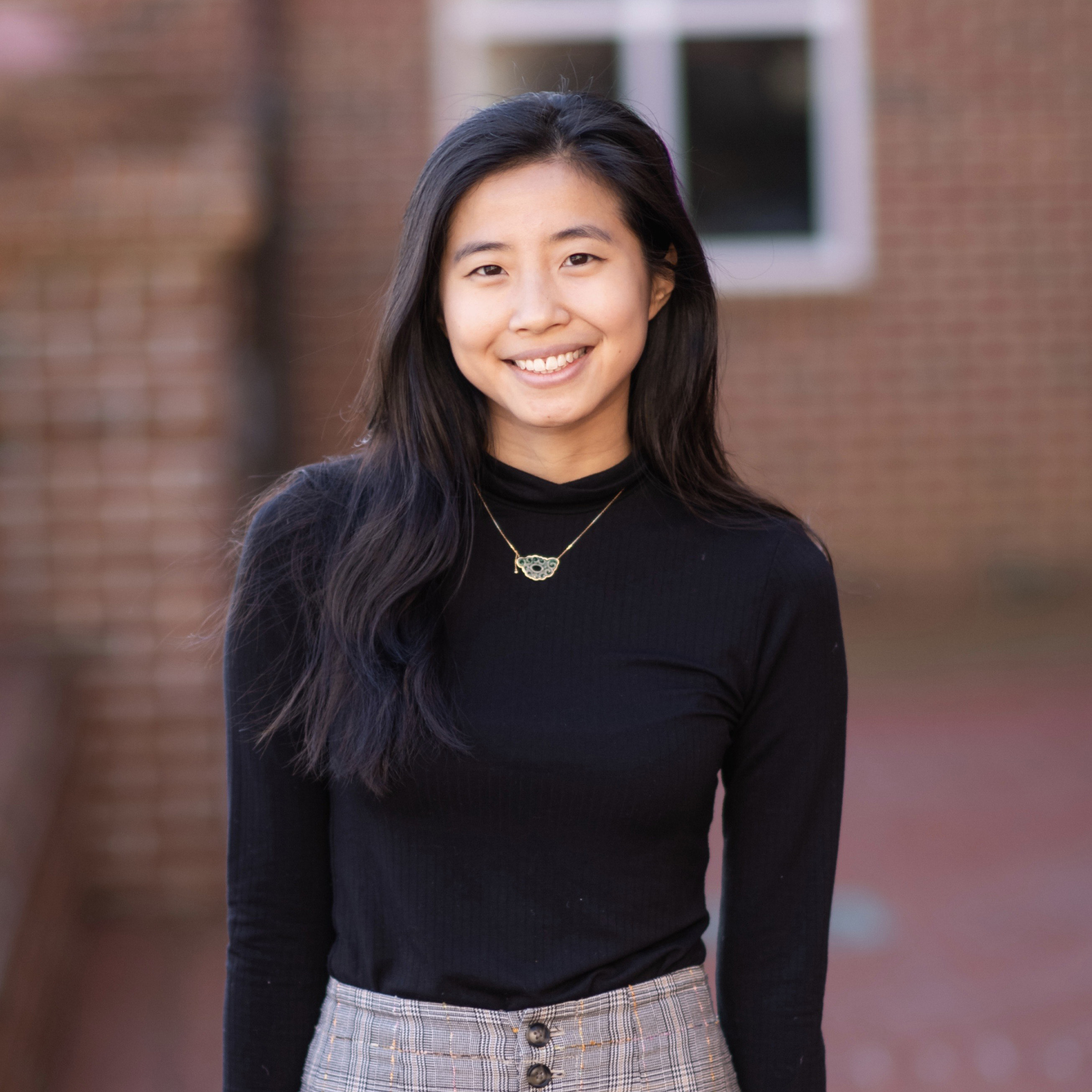 A person in a black shirt in front of a brick building