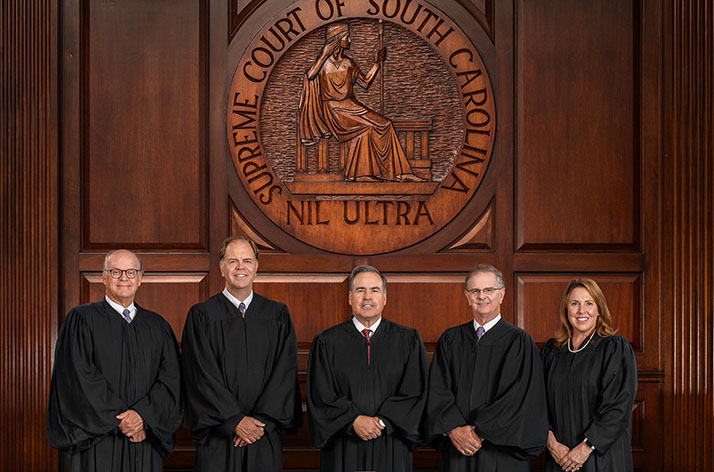 The South Carolina Supreme Court justices stand in front of their bench.