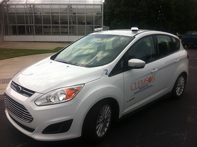 White hybrid vehicle with cameras on top for License Recognition. 