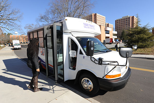 A female student is getting on the Research Park bus at the bus stop. 