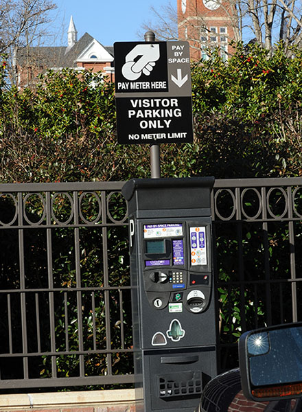 Visitor Parking sign over a parking meter showing where and how to pay for the metered space.   