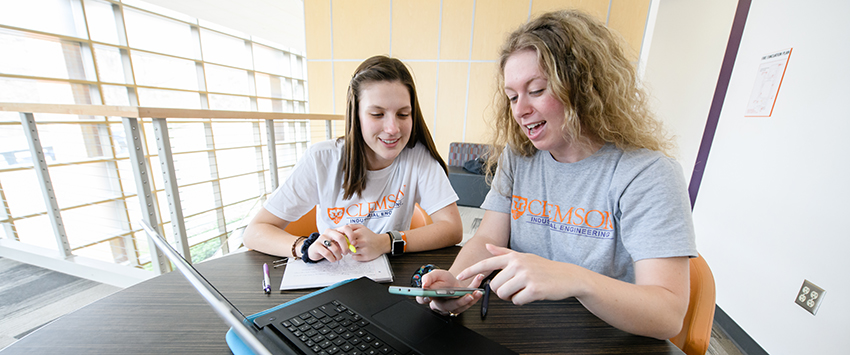 Students working with a laptop and phone.