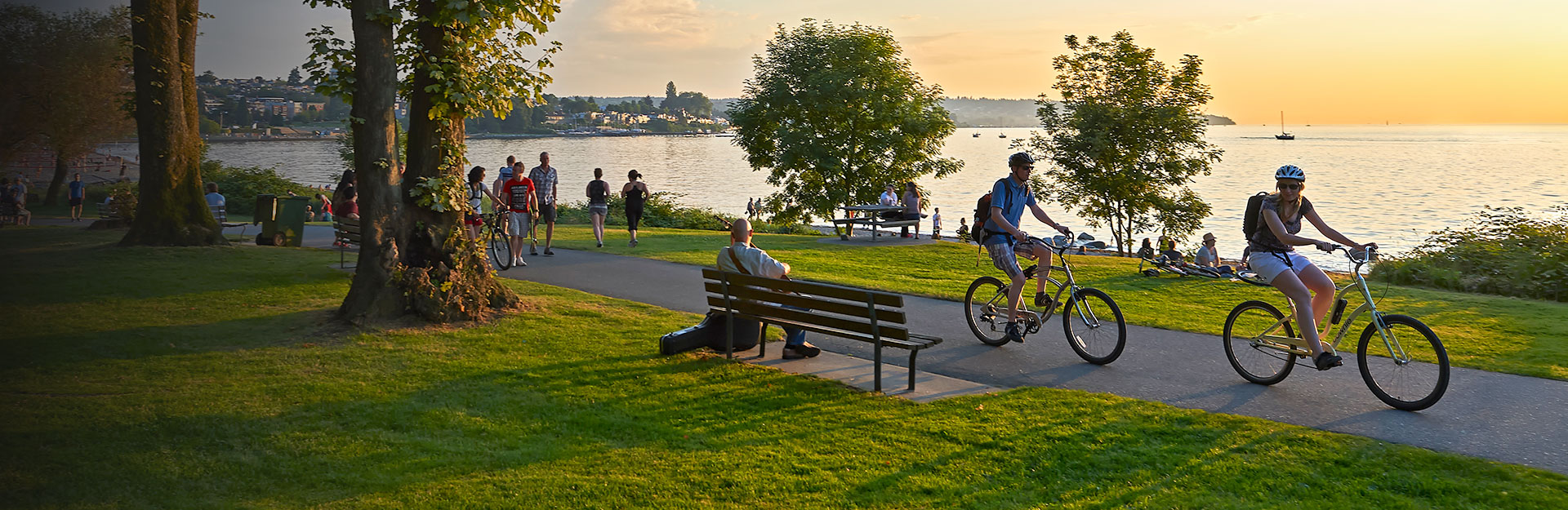 Young couple cycling, others walking or jogging late afternoon and enjoying the sunset at Stanley Park.