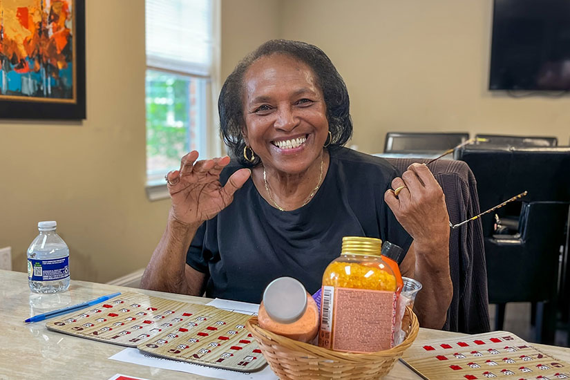 Older woman smiling at camera while playing bingo at a community center.