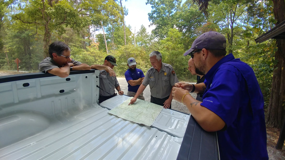 Clemson PRTM with park service researchers reviewing a map on the back of a truck flatbed.