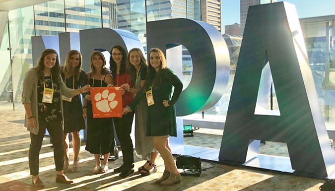 A photo of former EDGE students standing in front of a large NRPA logo display.