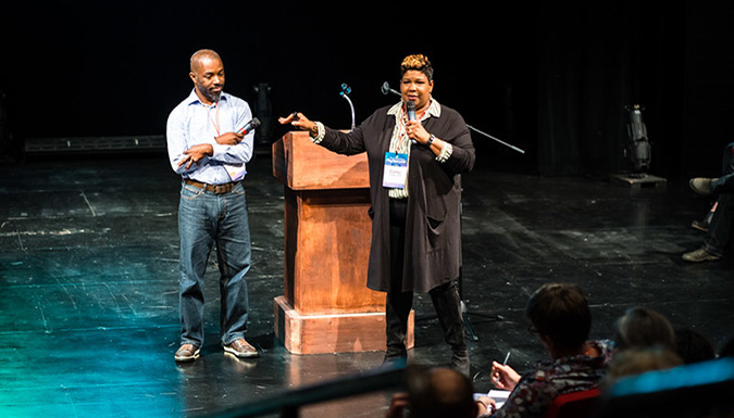 Photo of Drs. Pinckney and Outley presenting on a stage. 