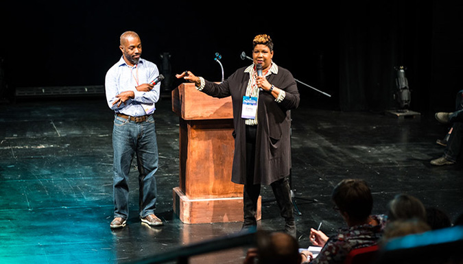 Photo of Drs. Pinckney and Outley presenting on a stage.
