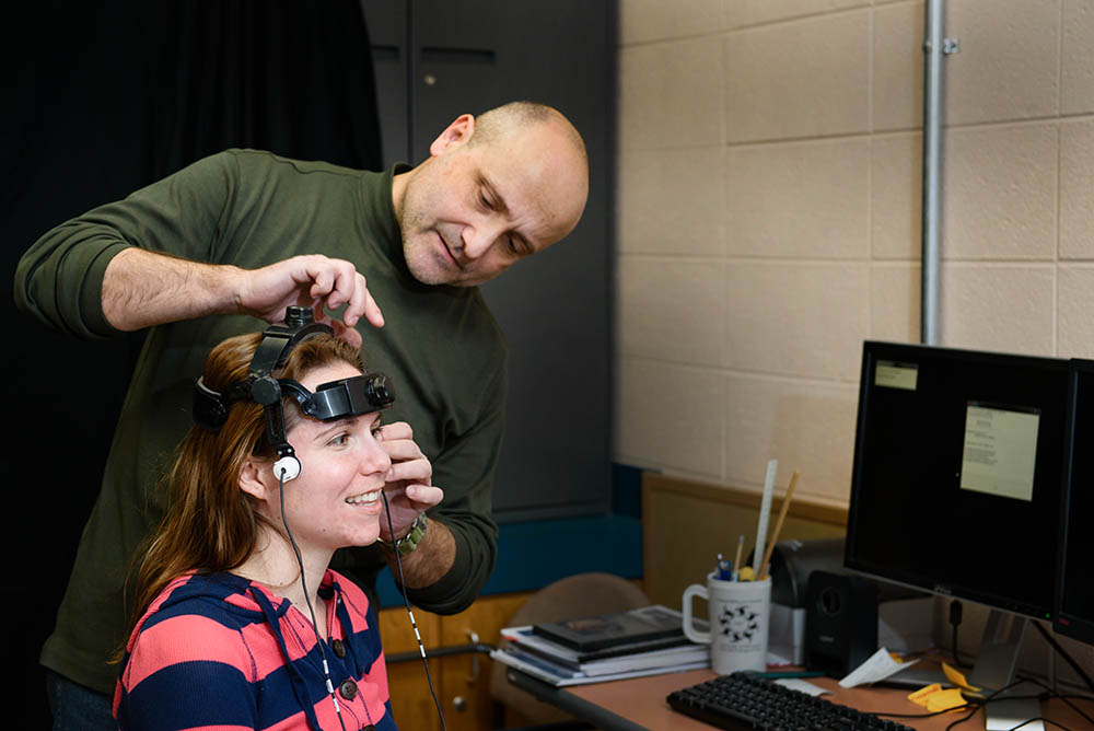 Man helping a woman who is wearing an electronic device on her head. 