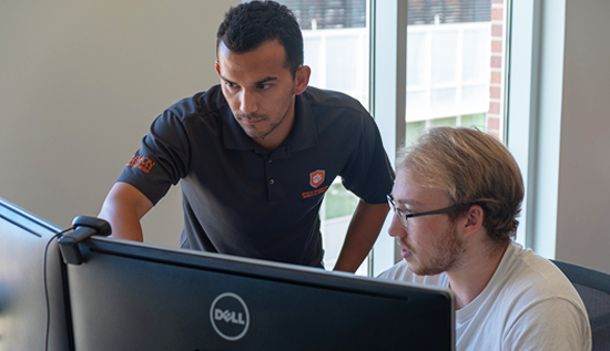 Office of Information Security employee working with someone at a computer.