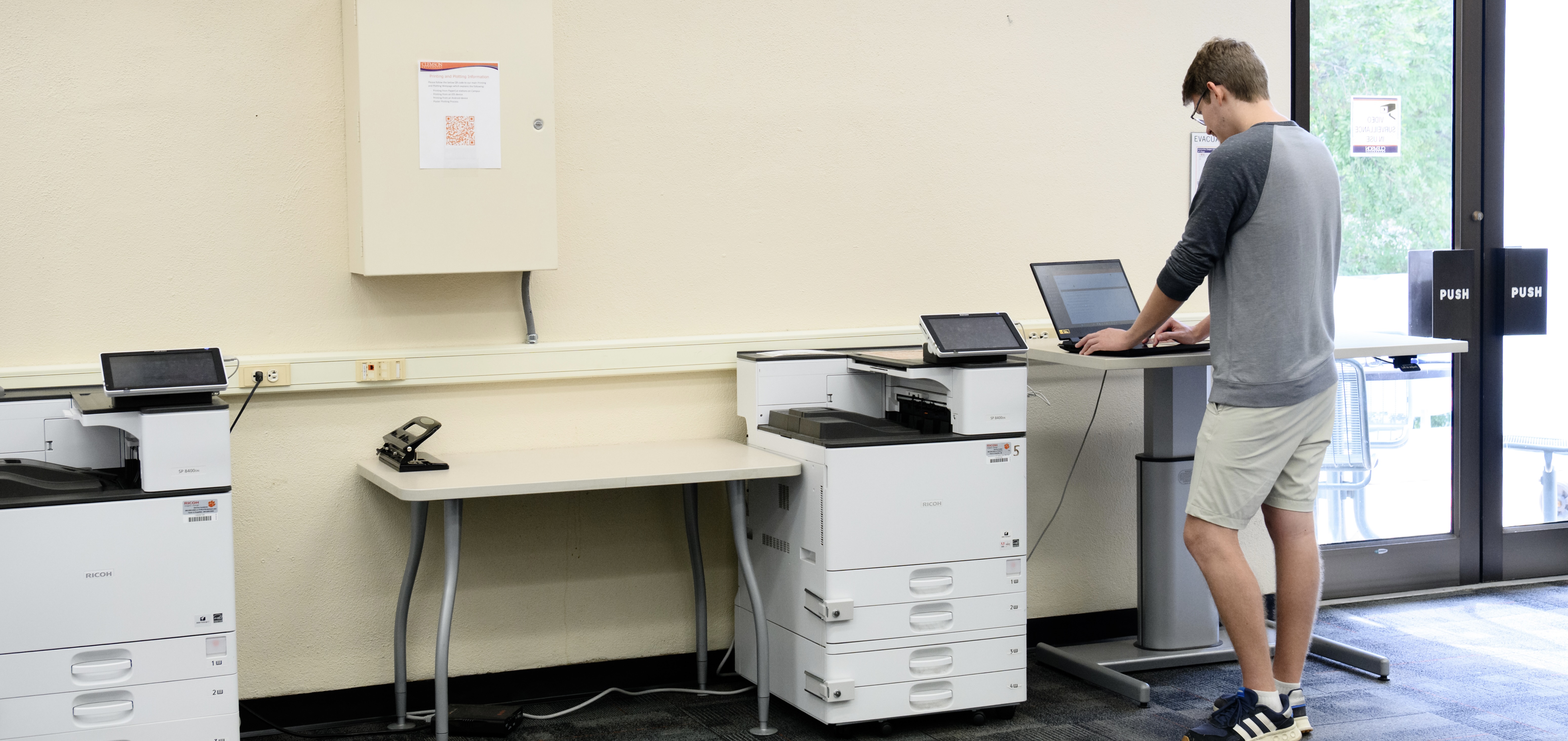 A student standing at a printer in the library.