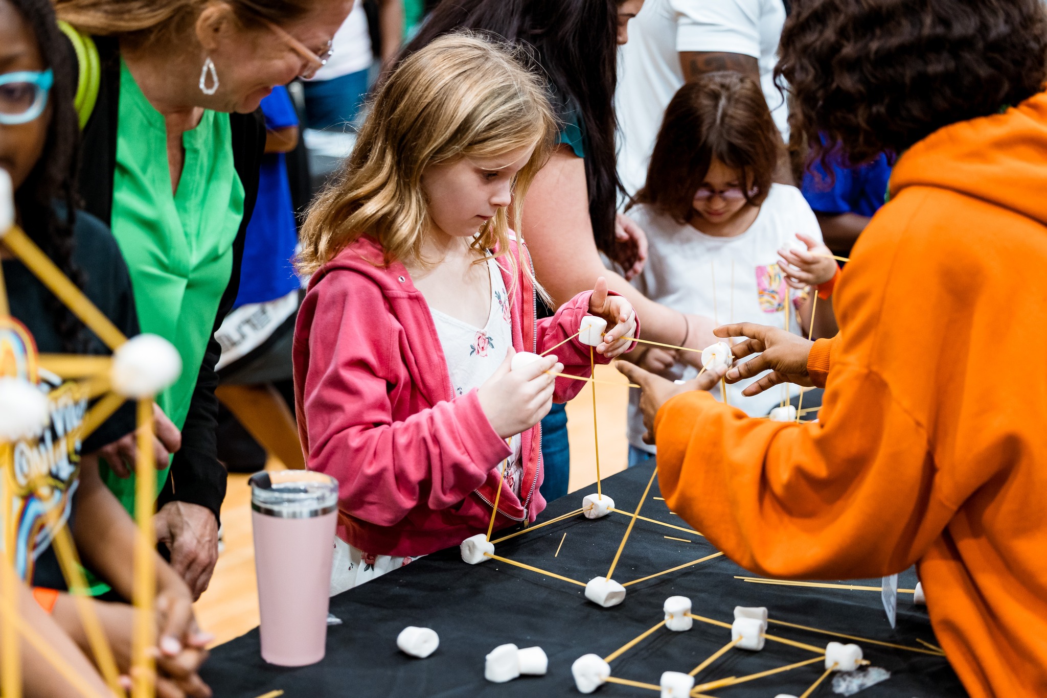 Female child in pink jacket bcompleting a building project during a STEM SC event