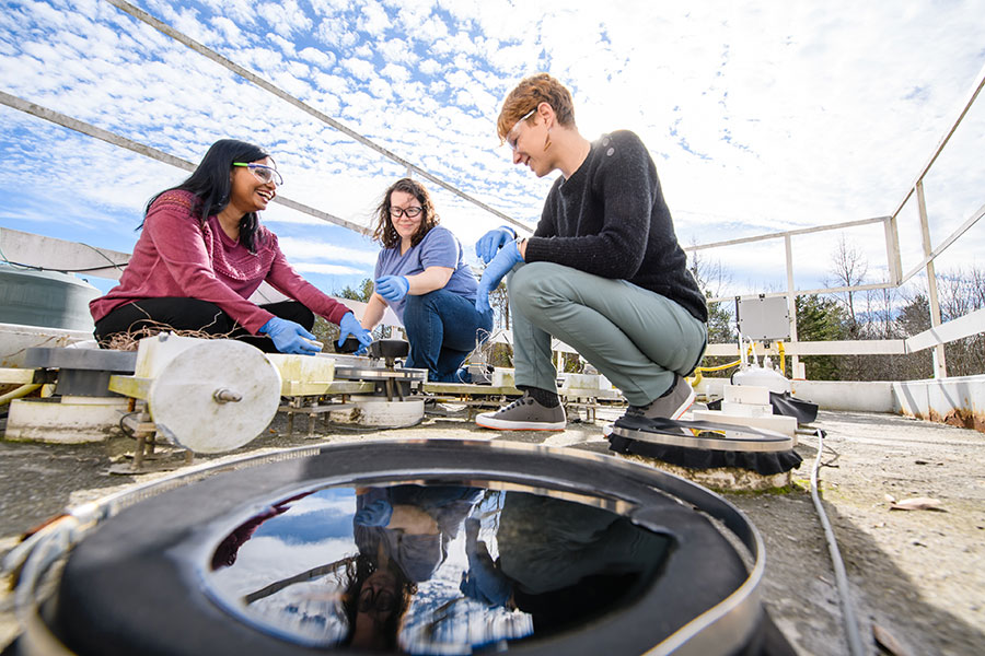 Three researchers involved in environmental engineering using a lysimeter