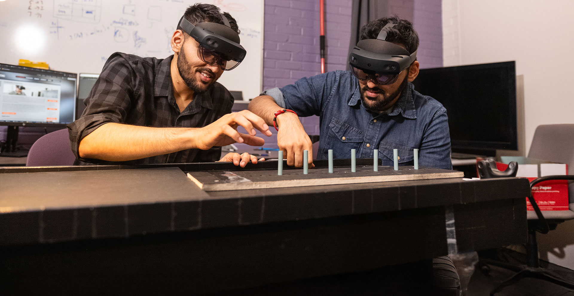Two graduate students in VR headsets working on research in human-centered computing.